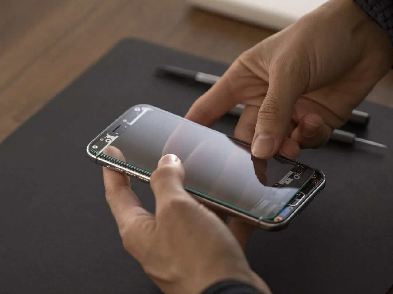 Mains posant un nouvel écran en verre sur un smartphone